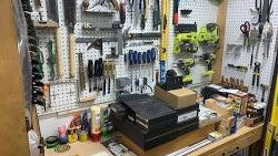 Atelier de bricolage organisé avec divers outils à main, perceuses et équipements de mesure sur un établi en bois.